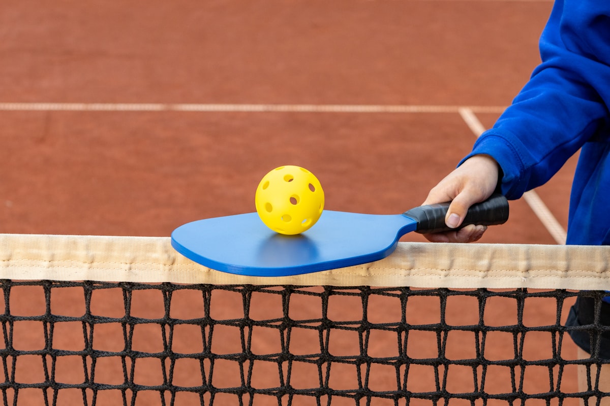 Pala de pickleball con la pelota apoyada sobre la red, listas para un dink