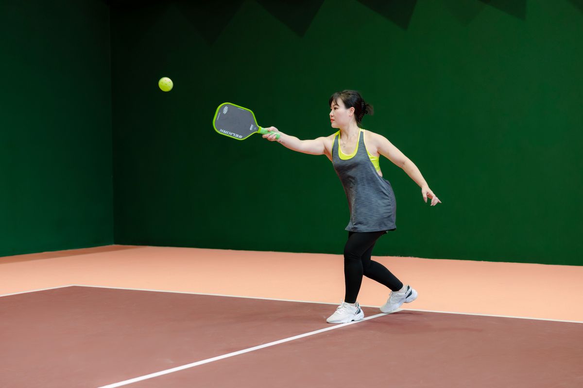 Jugadora golpeando con potencia en un partido de pickleball indoor