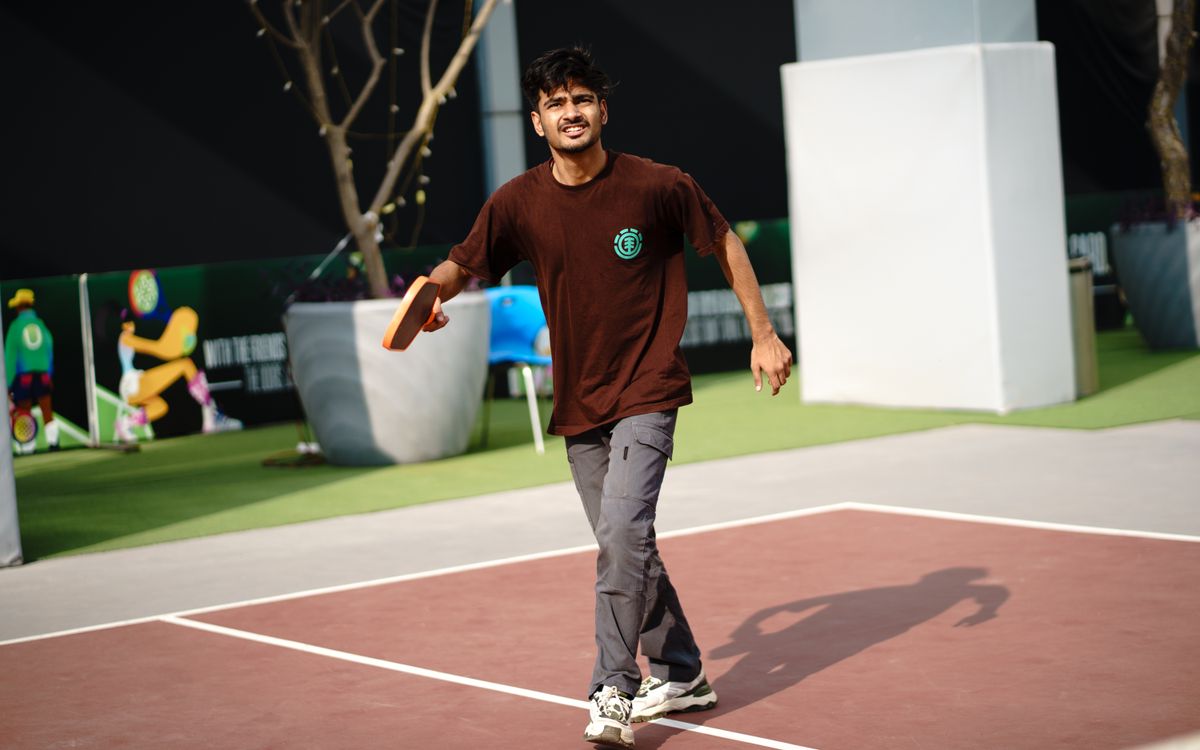 Jugador de pickleball golpeando la pelota en pista exterior
