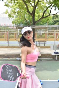 Mujer con ropa deportiva jugando a pickleball al aire libre